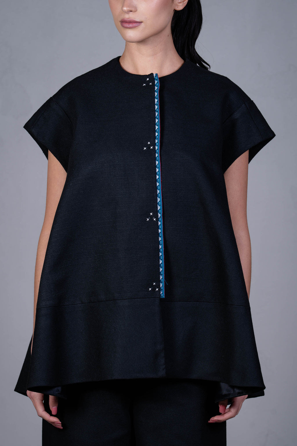 Black top with blue zipper on a gray background