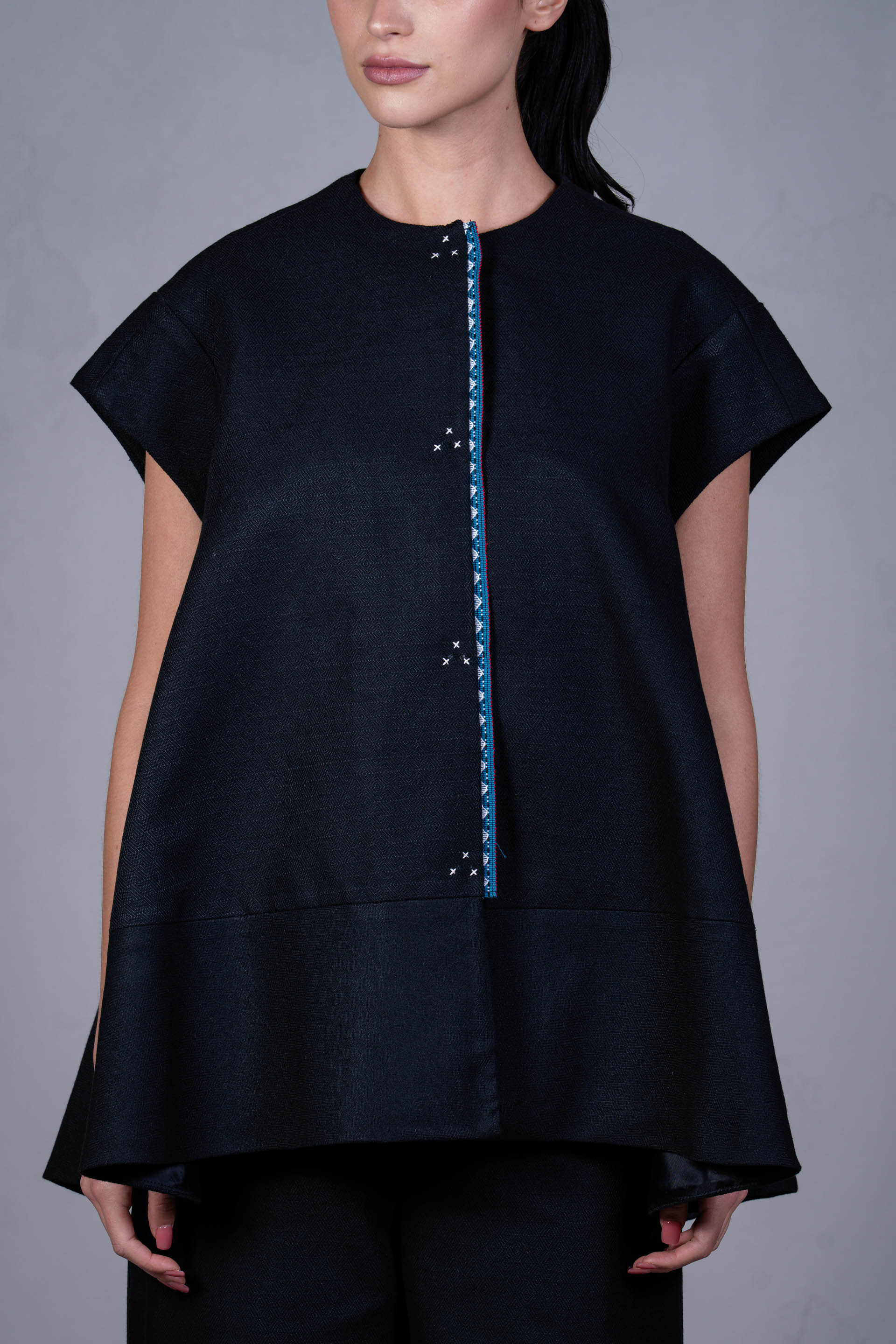 Black top with blue zipper on a gray background