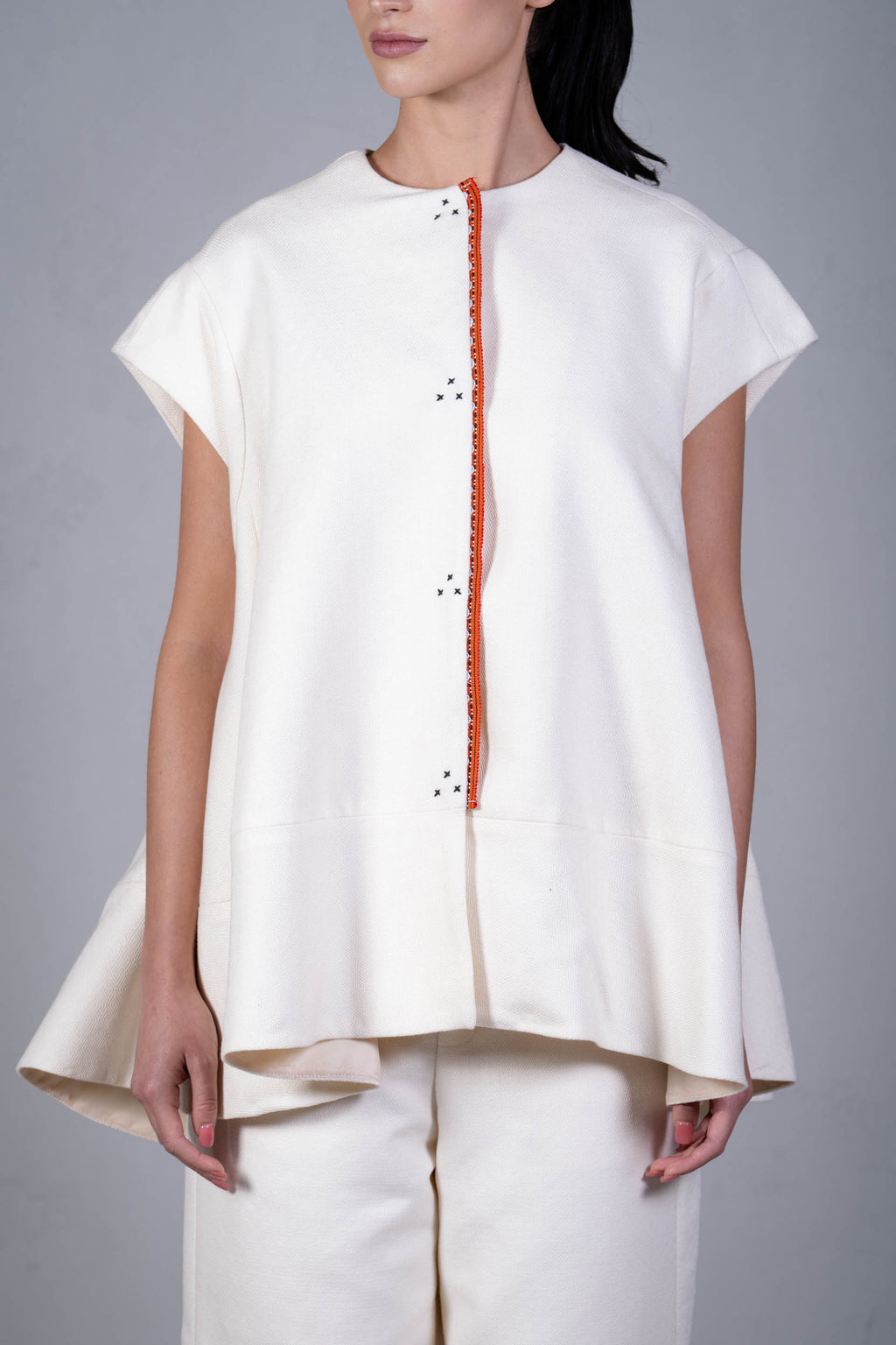 White sleeveless top with orange zipper on a gray background