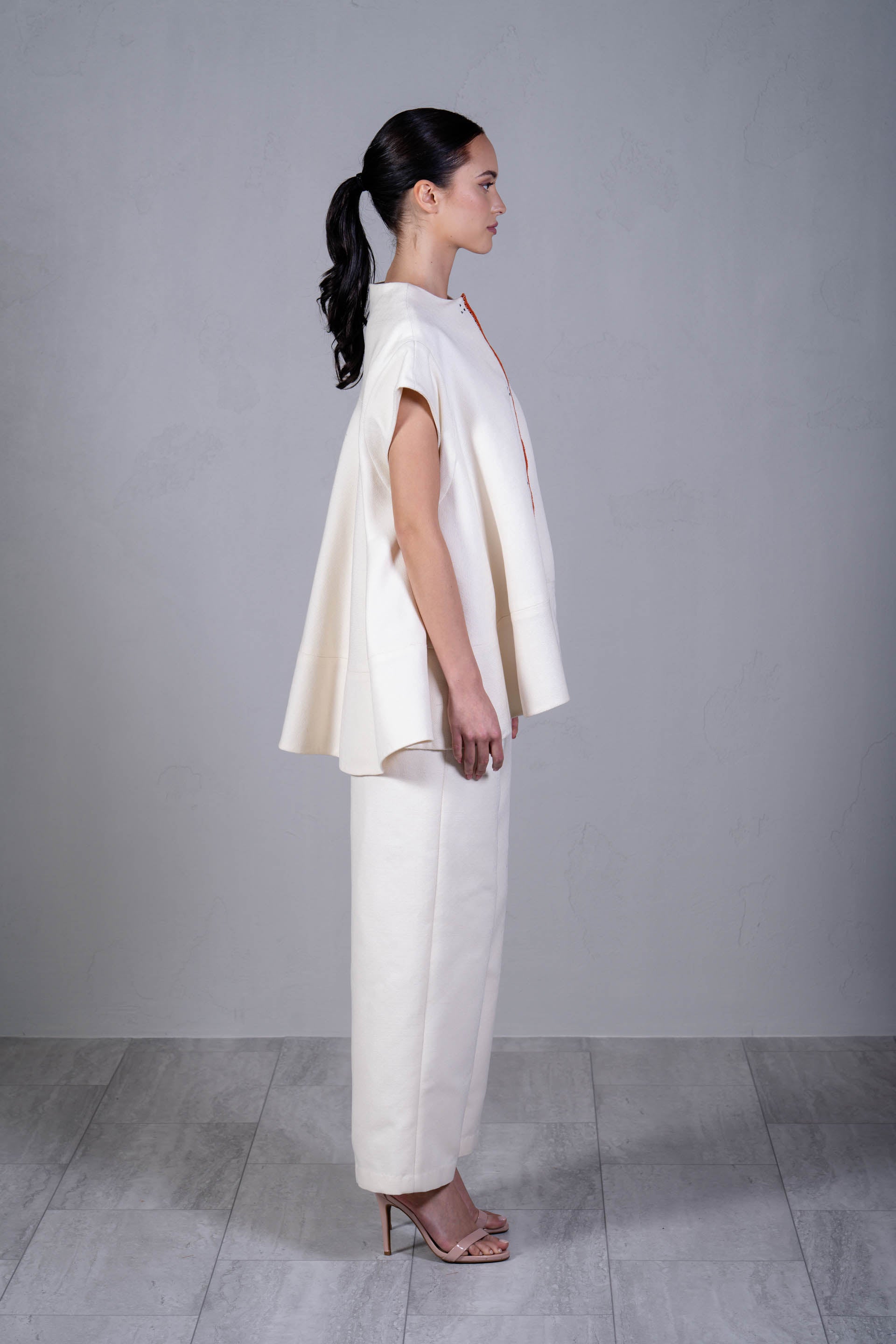 Woman wearing a white outfit standing against a plain gray background